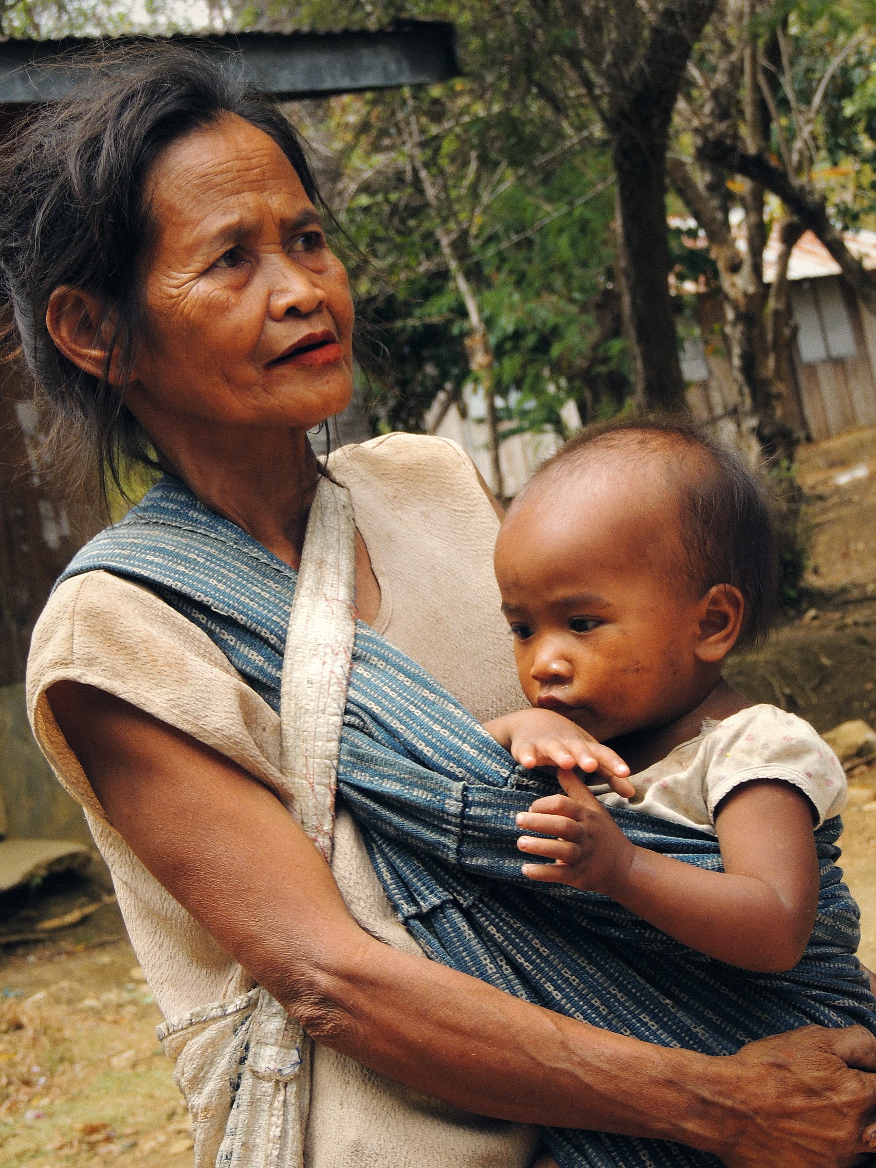 Eine Mutter trägt ihr Baby in einer ländlichen Gemeinde auf Mindoro
